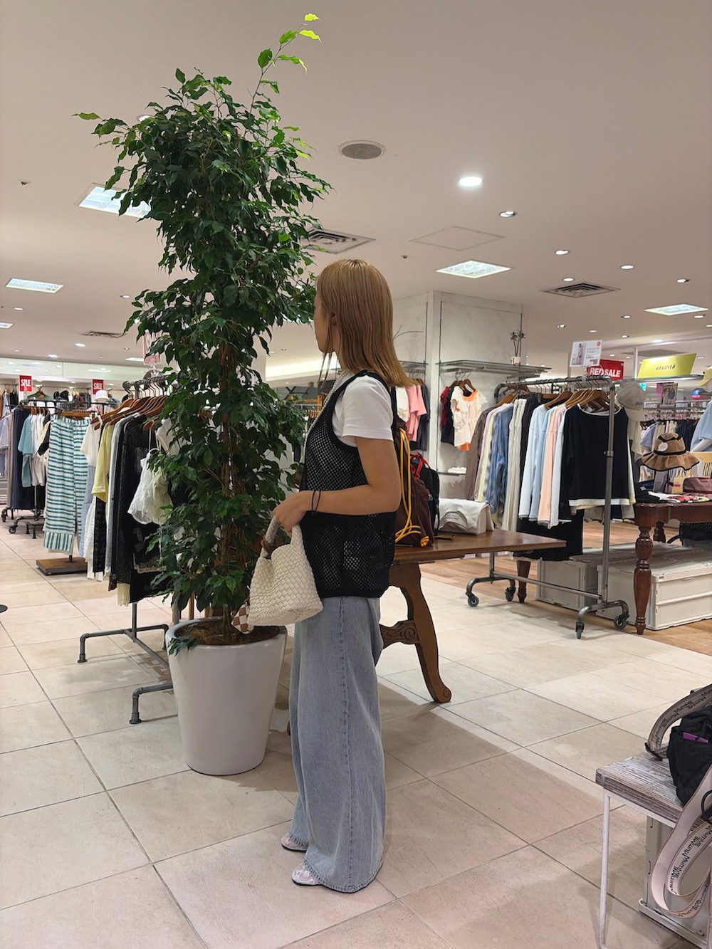 ブラック系のタンクトップ、ベージュ系のショルダーバッグ、ブルー系のデニムパンツを着用したレディースの夏コーディネートの3枚目の写真