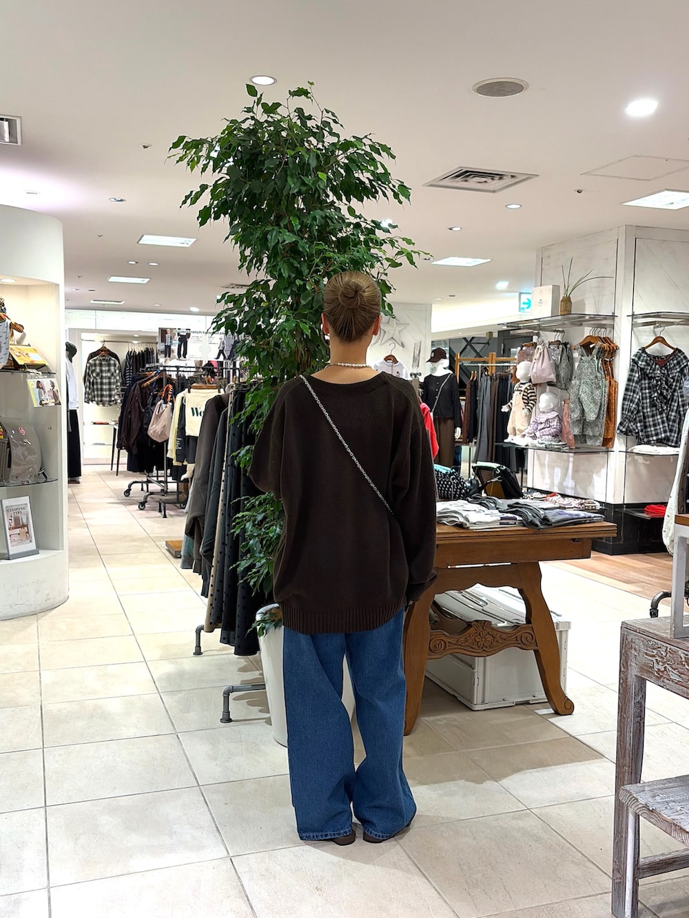 ブルー系のデニムパンツ、ブラウン系のカーディガン/ボレロ、ブラウン系のパンプスを着用したレディースの秋コーディネートの2枚目の写真