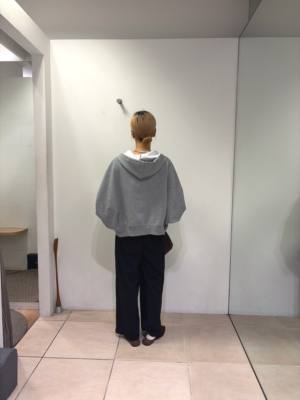 グレー系のパーカー、ブラック系のスラックス、ブラウン系のパンプスを着用したレディースの秋コーディネートの3枚目の写真