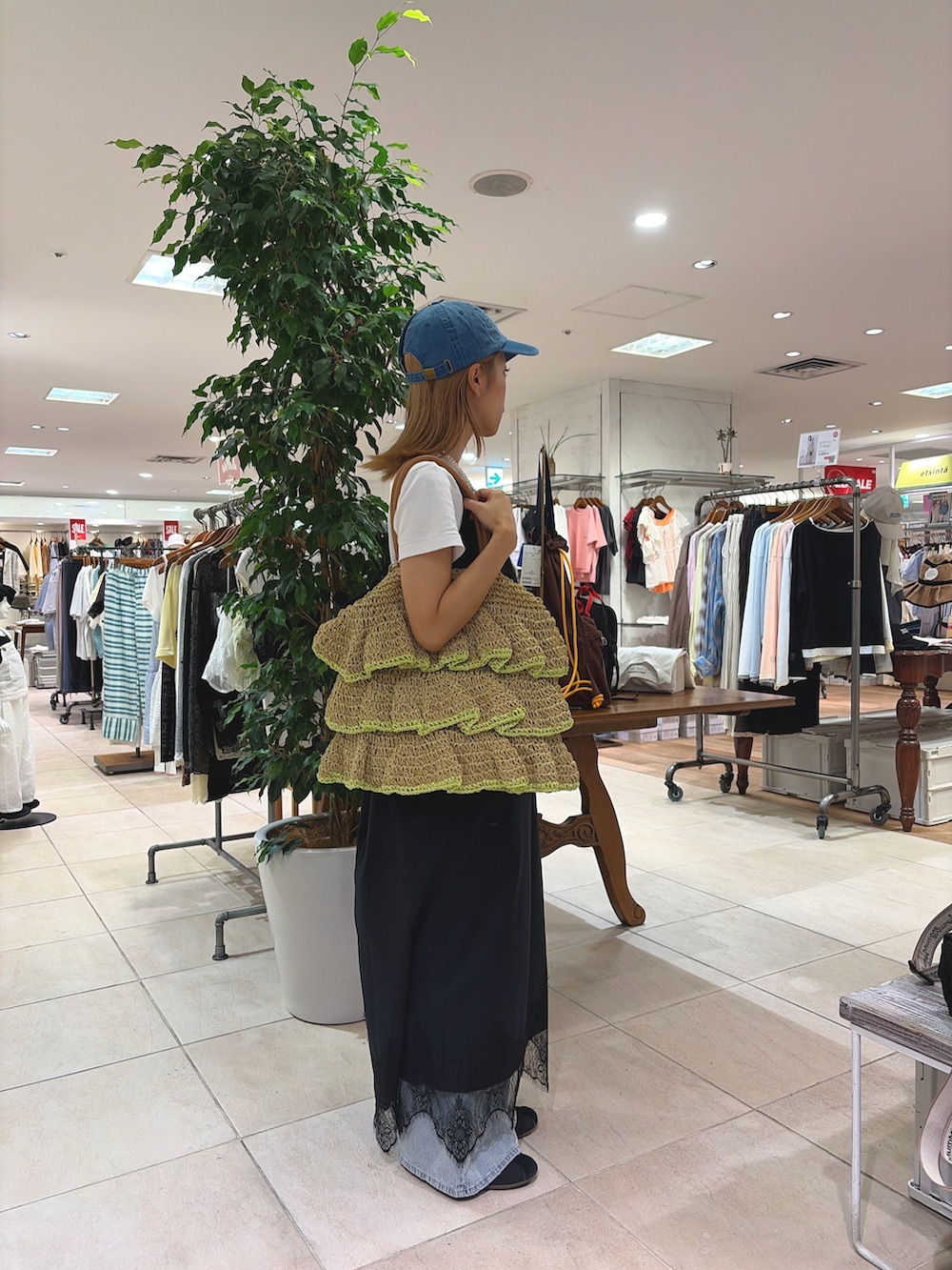 ブラック系のワンピース、ベージュ系のトートバッグ、ブルー系のデニムパンツを着用したレディースの夏コーディネートの2枚目の写真