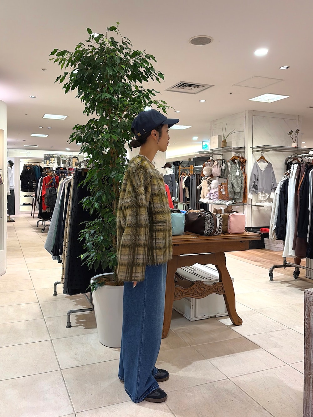 グリーン系のカーディガン/ボレロ、ブルー系のデニムパンツ、ブルー系のキャップを着用したレディースの秋コーディネートの3枚目の写真
