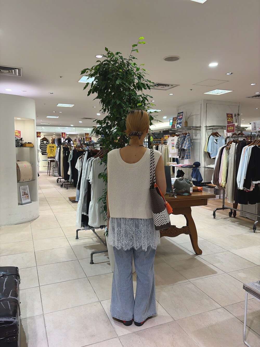 ホワイト系のベスト、ブルー系のデニムパンツ、ブラウン系のトートバッグを着用したレディースの夏コーディネートの2枚目の写真