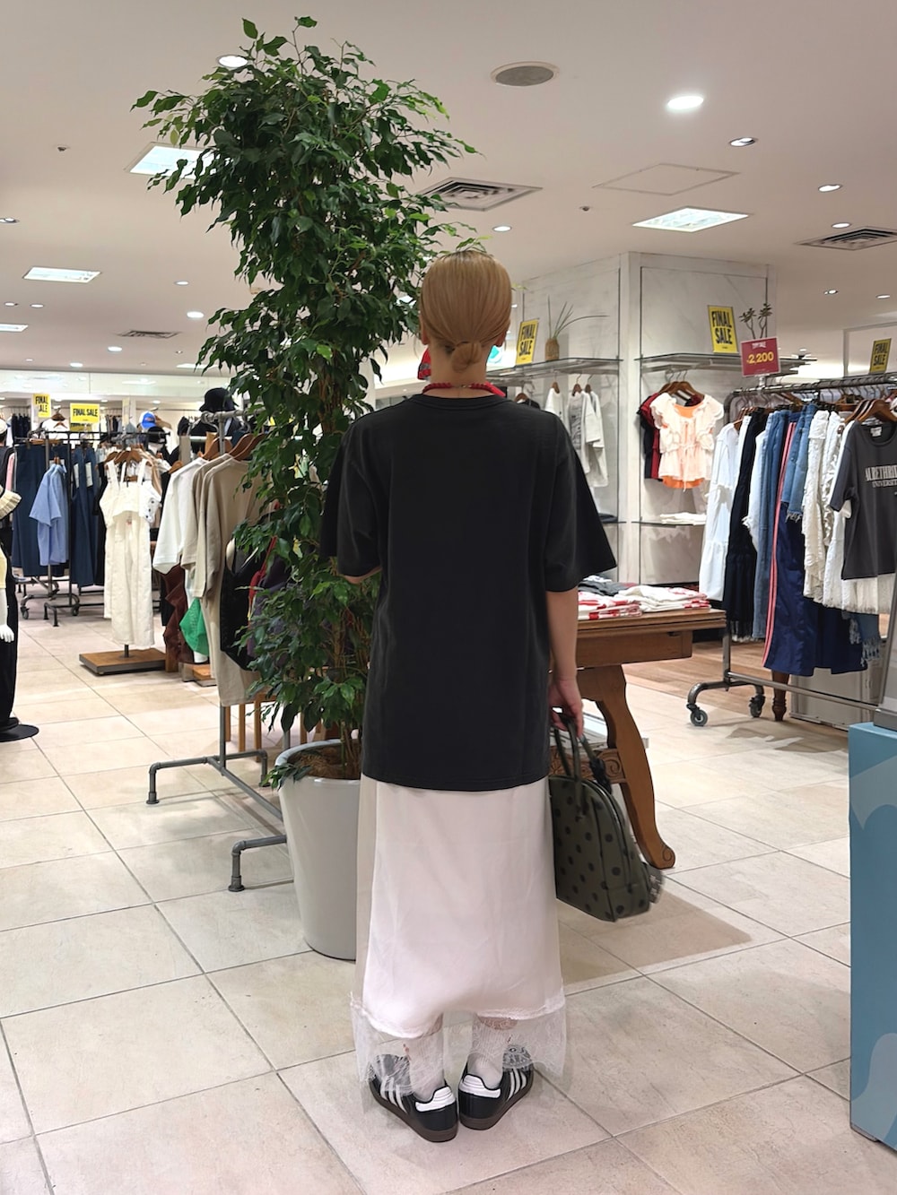 ブラック系のTシャツ/カットソー、ホワイト系のスカート、グリーン系のショルダーバッグを着用したレディースの夏コーディネートの3枚目の写真