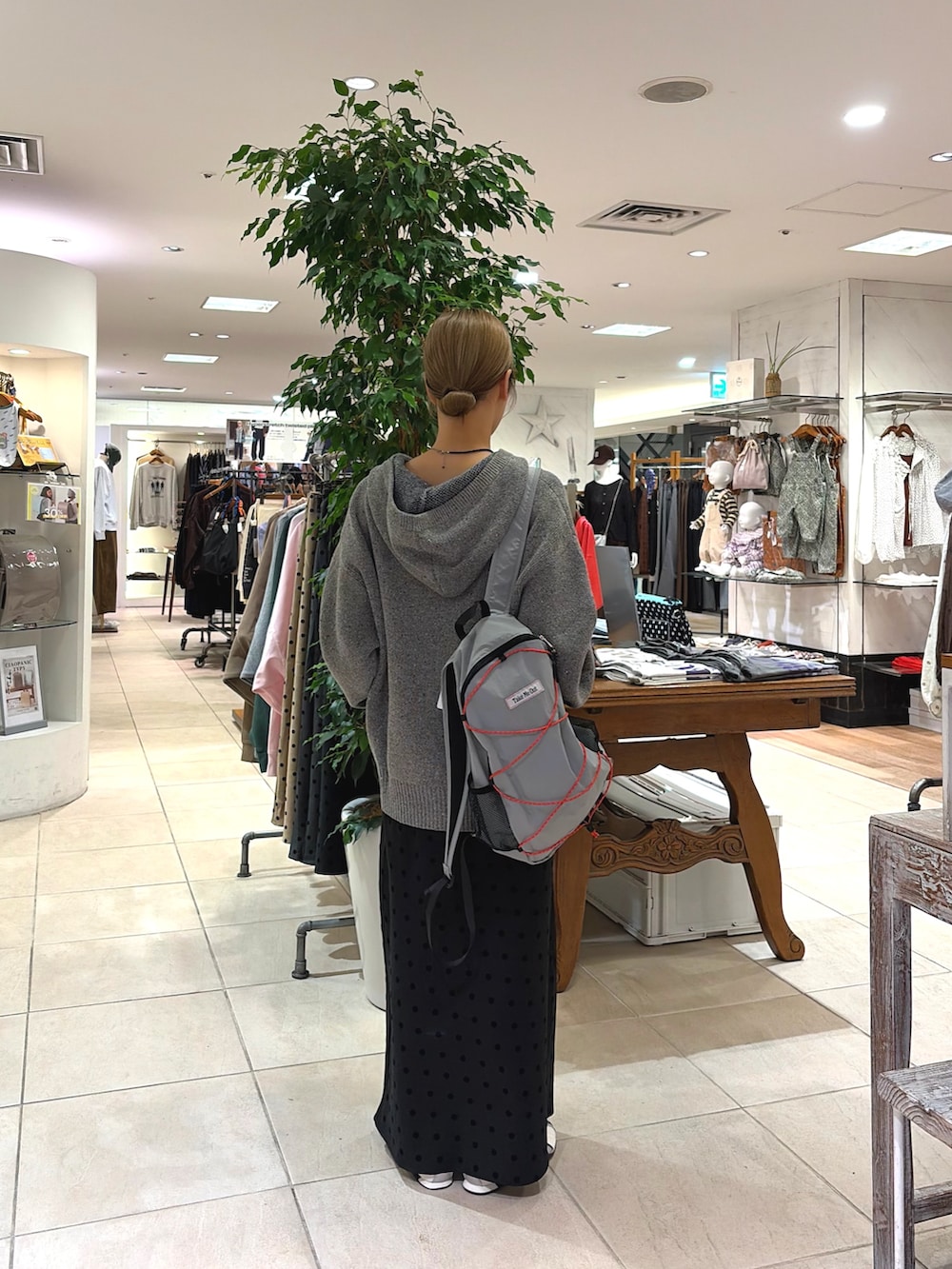 グレー系のパーカー、ブラック系のスカート、グレー系のバックパック/リュックを着用したレディースの秋コーディネートの3枚目の写真