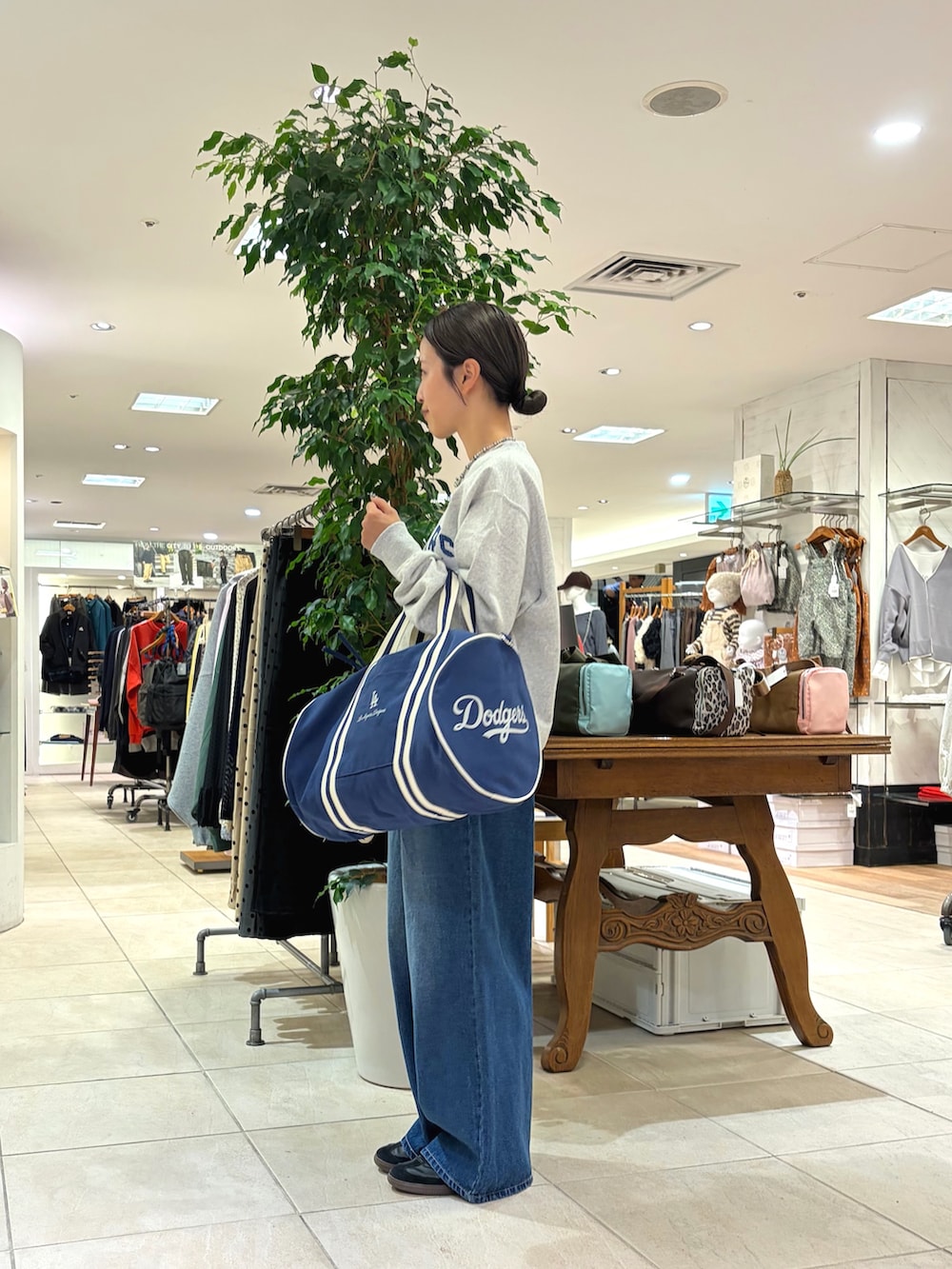 グレー系のスウェット、ブルー系のボストンバッグ、ブルー系のデニムパンツを着用したレディースの秋コーディネートの2枚目の写真