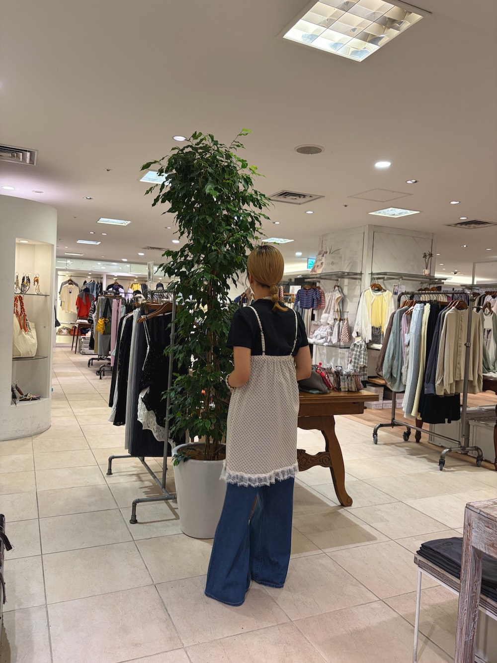 ホワイト系のチュニック、ブルー系のデニムパンツを着用したレディースの春コーディネートの2枚目の写真