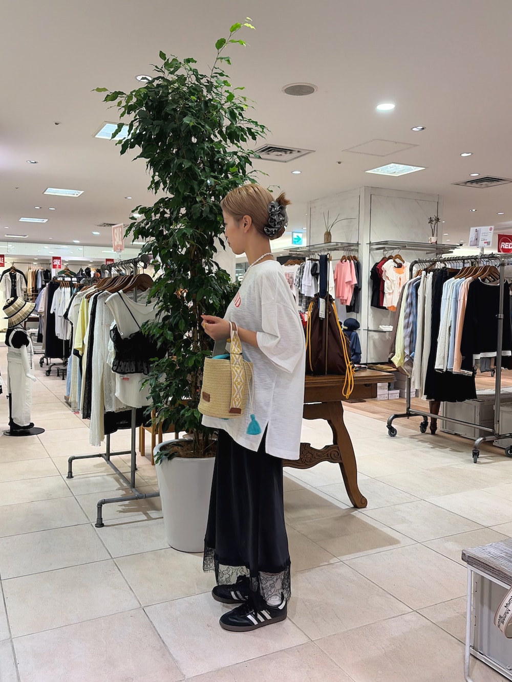 ホワイト系のTシャツ/カットソー、ベージュ系のトートバッグ、ブラック系のスカートを着用したレディースの夏コーディネートの2枚目の写真