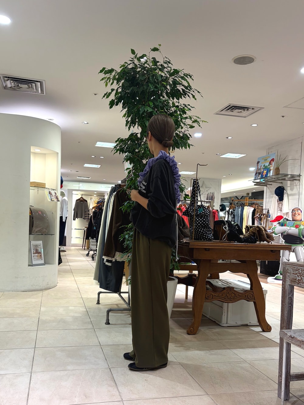 ブラック系のTシャツ/カットソー、ブラウン系のショルダーバッグ、グリーン系のスラックスを着用したレディースの秋コーディネートの3枚目の写真