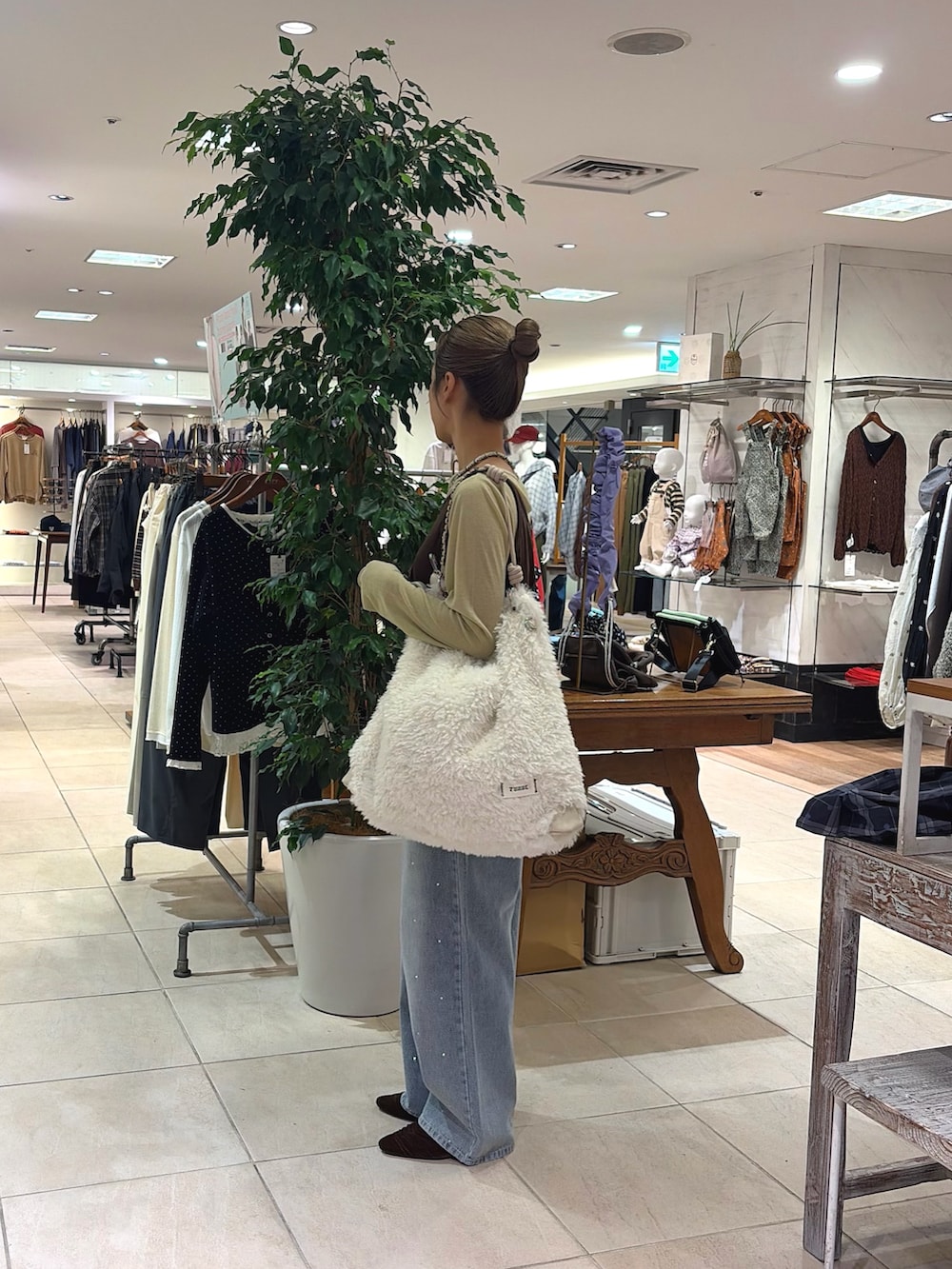 ブラウン系のTシャツ/カットソー、ホワイト系のショルダーバッグ、ブルー系のデニムパンツを着用したレディースの秋コーディネートの3枚目の写真