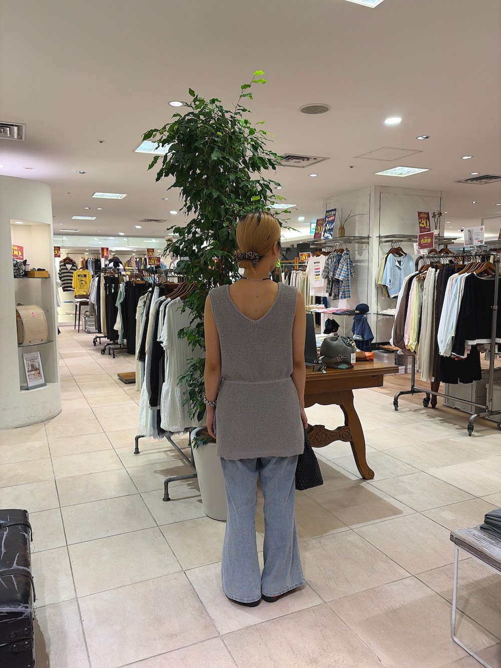 グレー系のベスト、ブルー系のデニムパンツ、ブラック系のショルダーバッグを着用したレディースの夏コーディネートの3枚目の写真