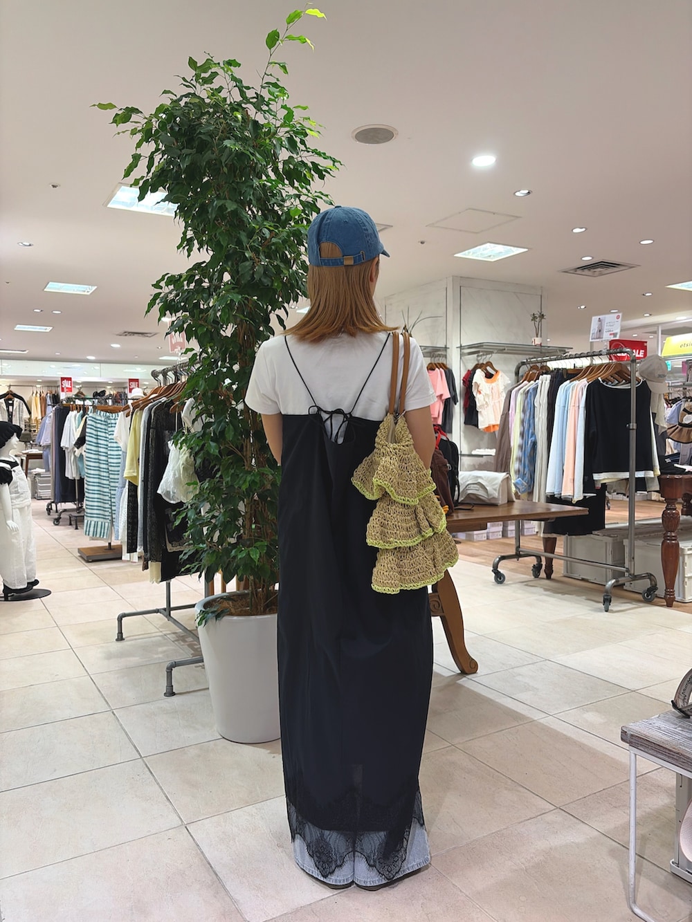 ブラック系のワンピース、ベージュ系のトートバッグ、ブルー系のデニムパンツを着用したレディースの夏コーディネートの4枚目の写真