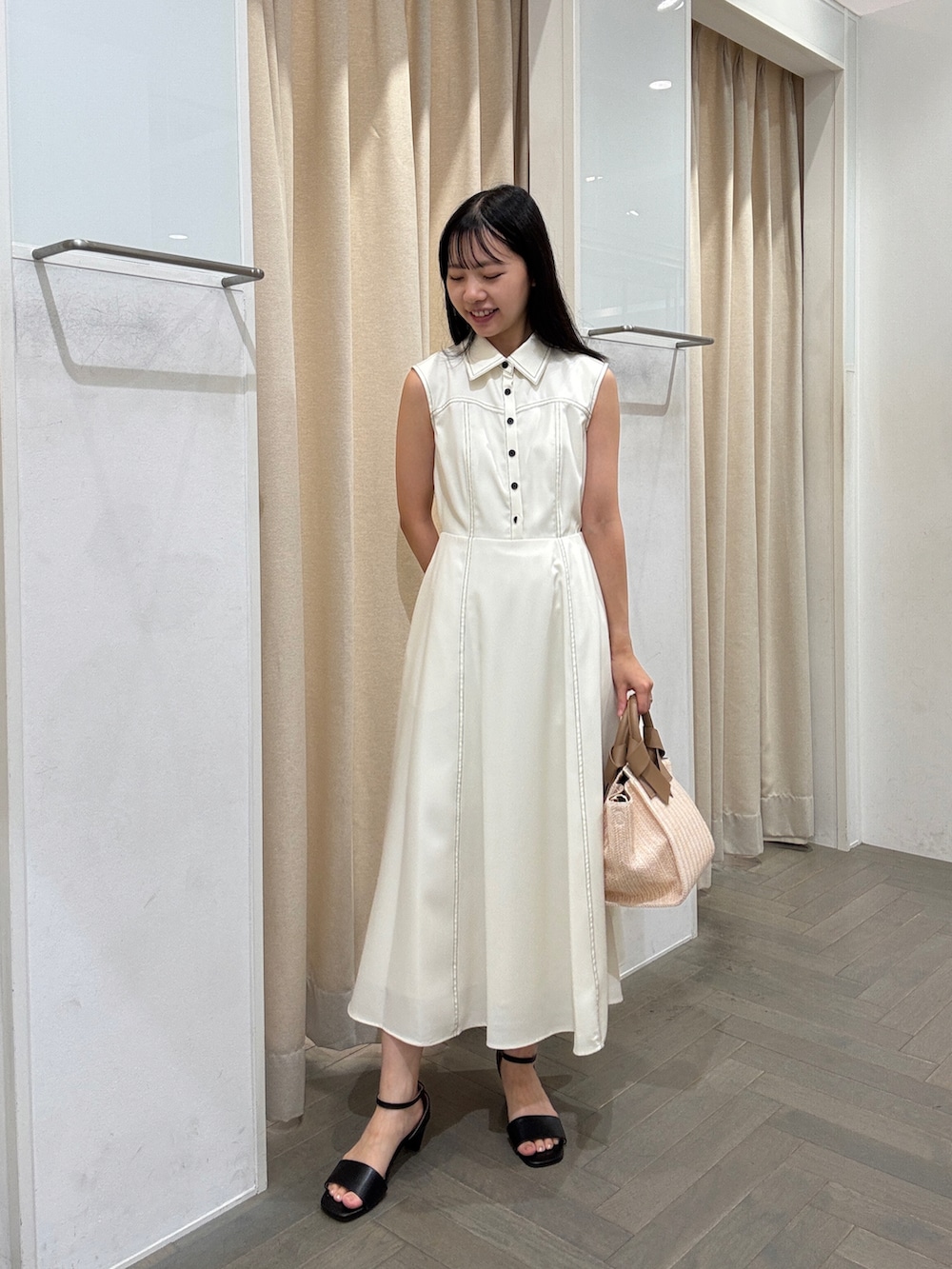 ホワイト系のワンピース、ホワイト系のトートバッグ、ブラック系のサンダルを着用したレディースの夏コーディネートの2枚目の写真