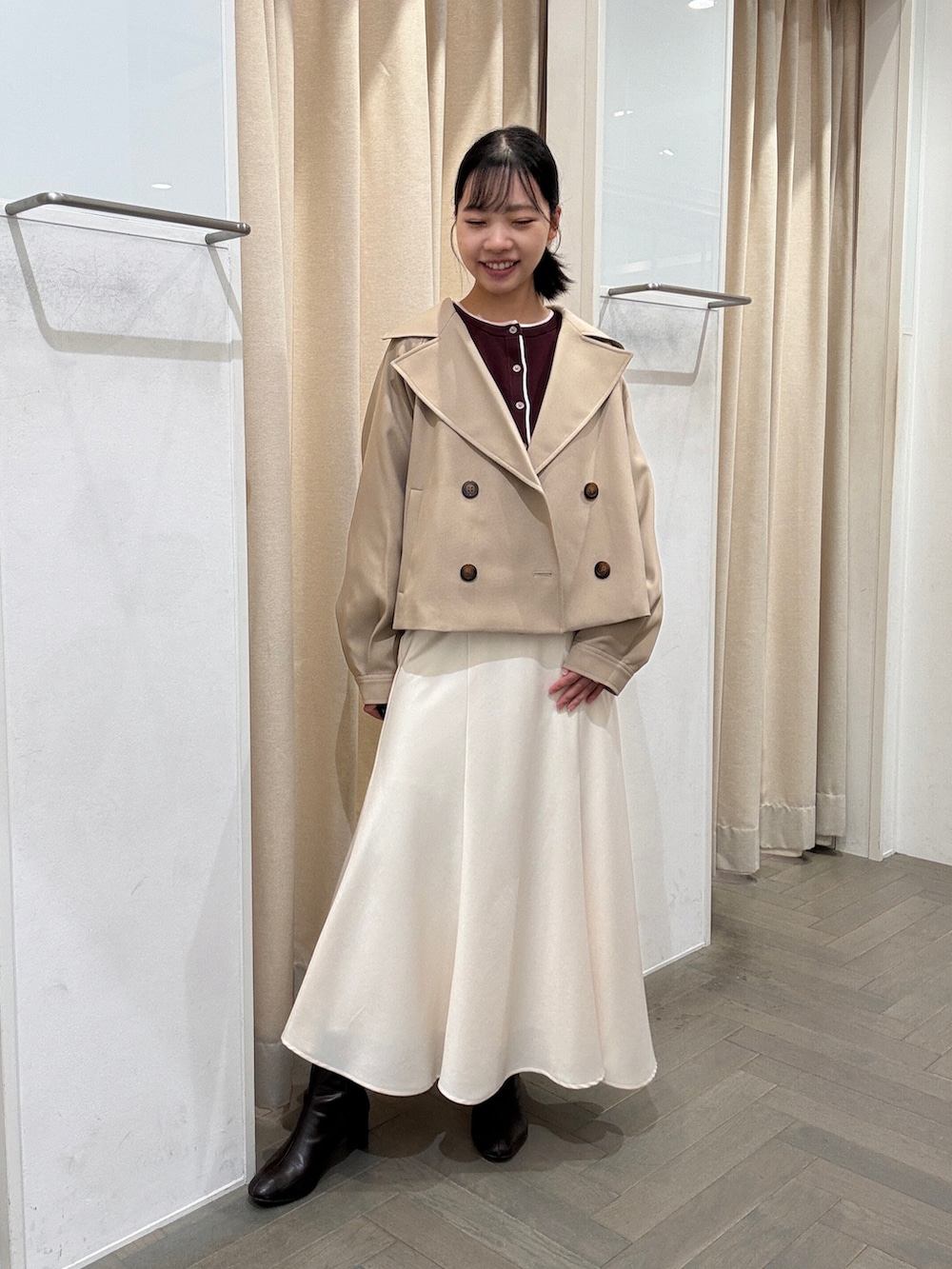 ベージュ系のトレンチコート、レッド系のカーディガン/ボレロ、ホワイト系のスカートを着用したレディースの秋コーディネートの2枚目の写真
