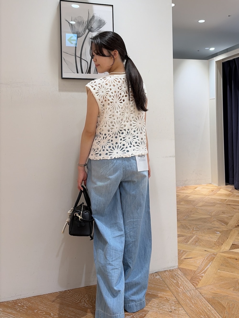 ホワイト系のベスト、ブルー系のデニムパンツ、ブラック系のサンダルを着用したレディースの夏コーディネートの5枚目の写真