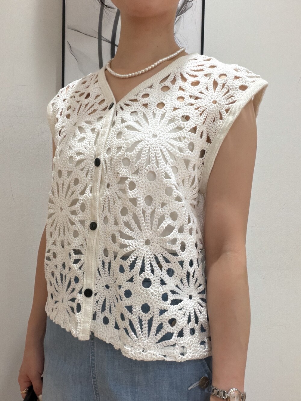 ホワイト系のベスト、ブルー系のデニムパンツ、ブラック系のサンダルを着用したレディースの夏コーディネートの6枚目の写真