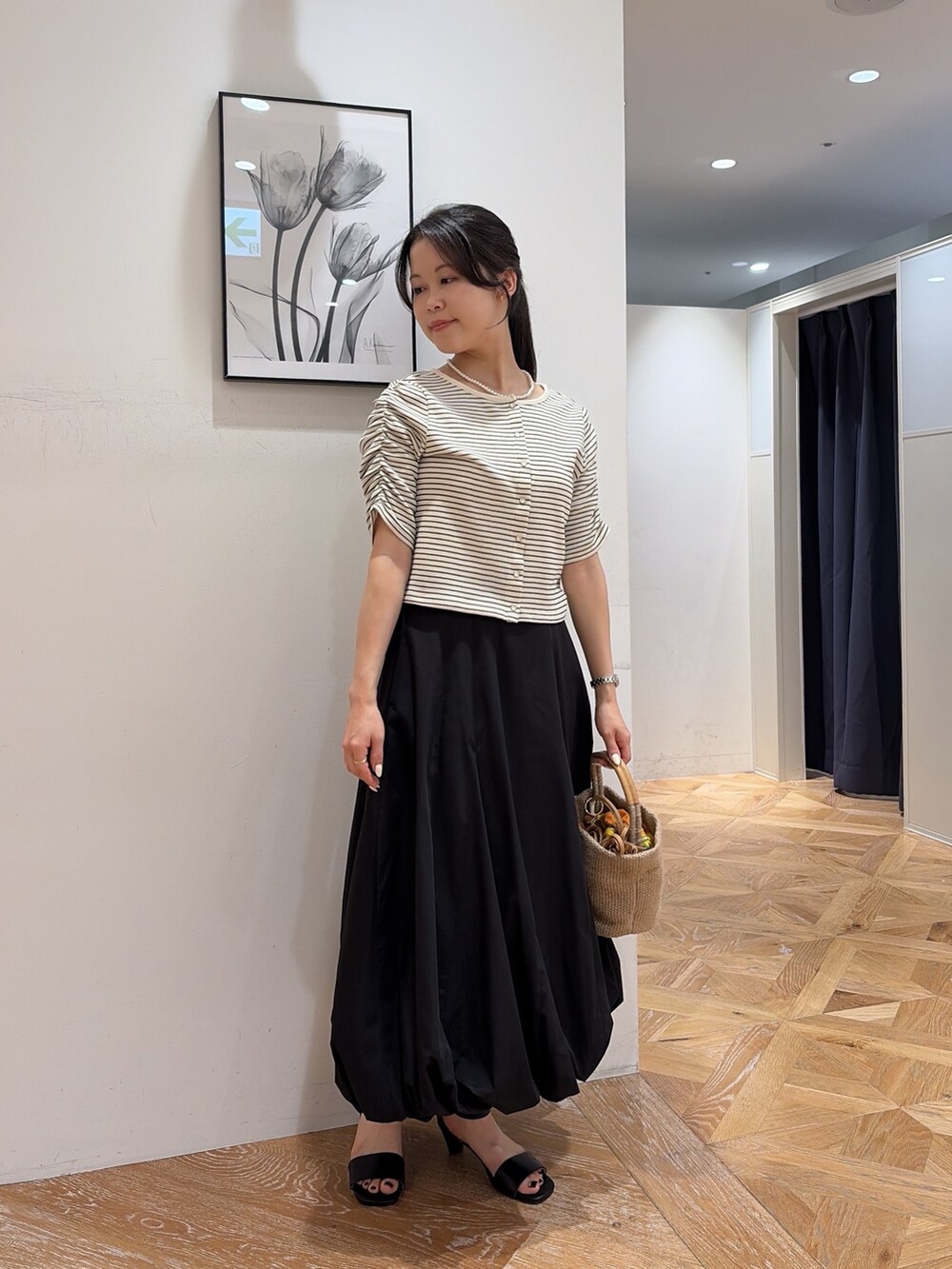 ホワイト系のTシャツ/カットソー、ブラック系のスカート、ベージュ系のショルダーバッグを着用したレディースの夏コーディネートの2枚目の写真