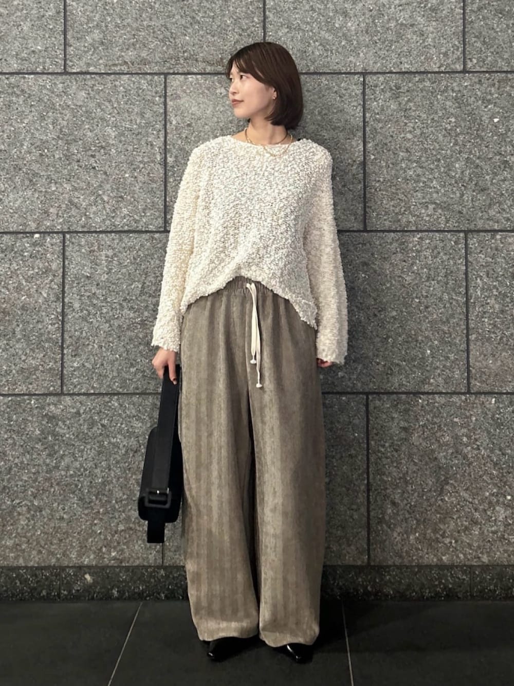 ホワイト系のニット/セーター、ベージュ系のその他パンツ、ブラック系のトートバッグを着用したレディースの秋コーディネートの4枚目の写真