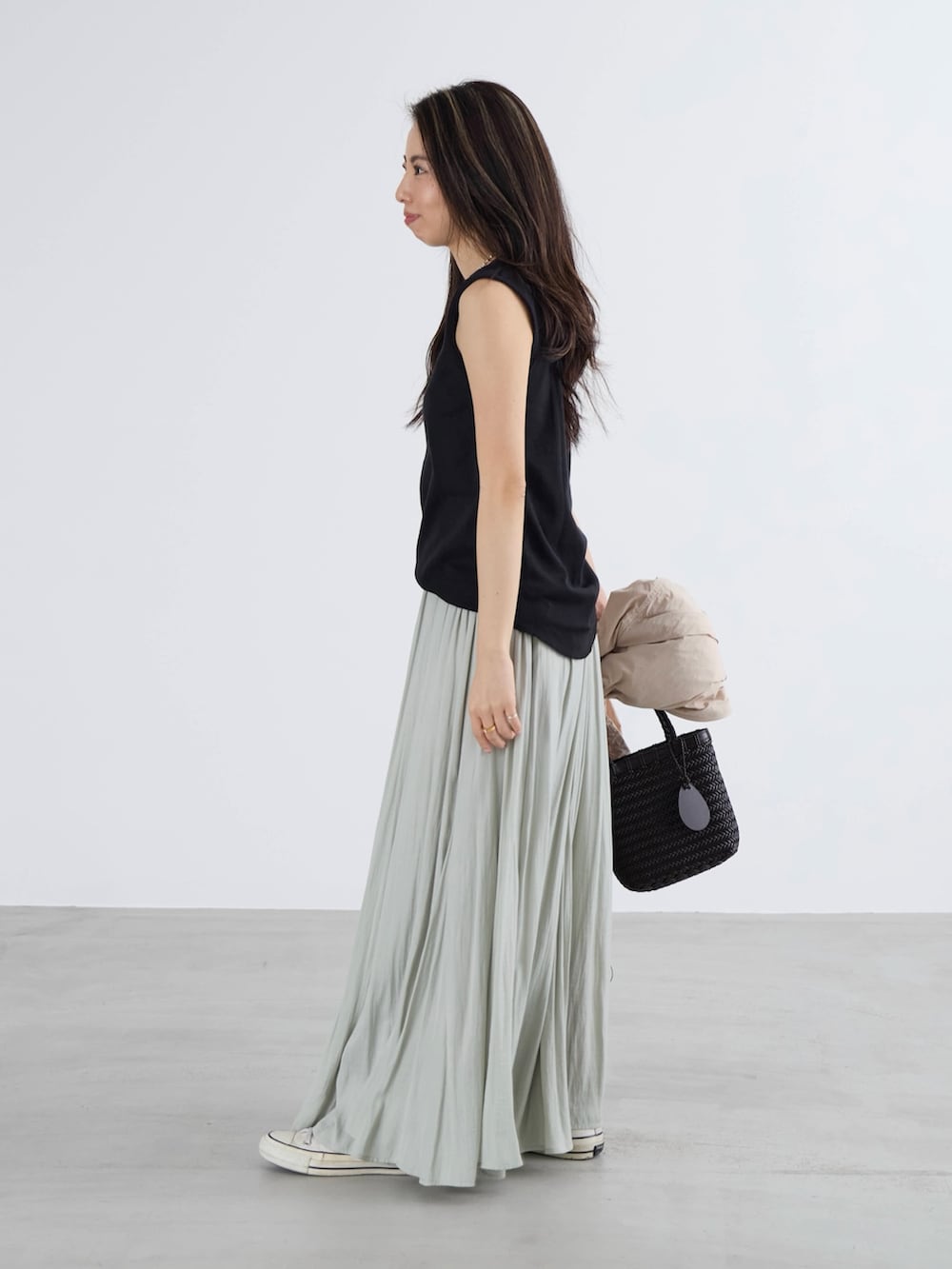 グリーン系のスカート、ブラック系のTシャツ/カットソーを着用したレディースの春コーディネートの2枚目の写真