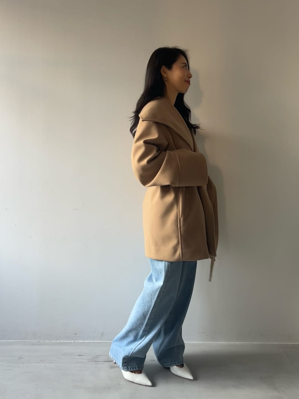 イエロー系のその他アウター、グレー系のニット/セーター、ブルー系のデニムパンツを着用したレディースの冬コーディネートの2枚目の写真