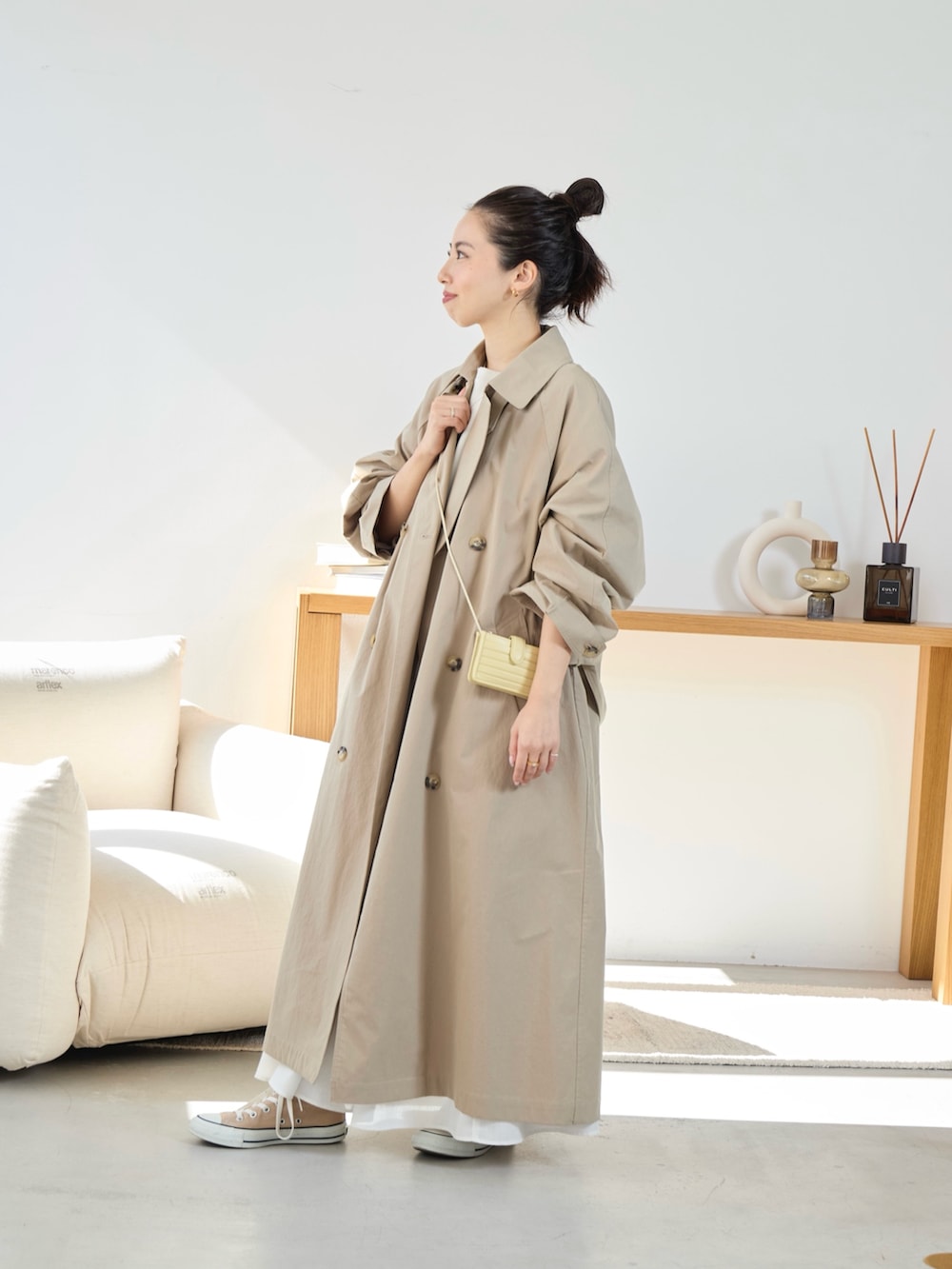 ベージュ系のトレンチコート、ホワイト系のスカートを着用したレディースの冬コーディネートの2枚目の写真