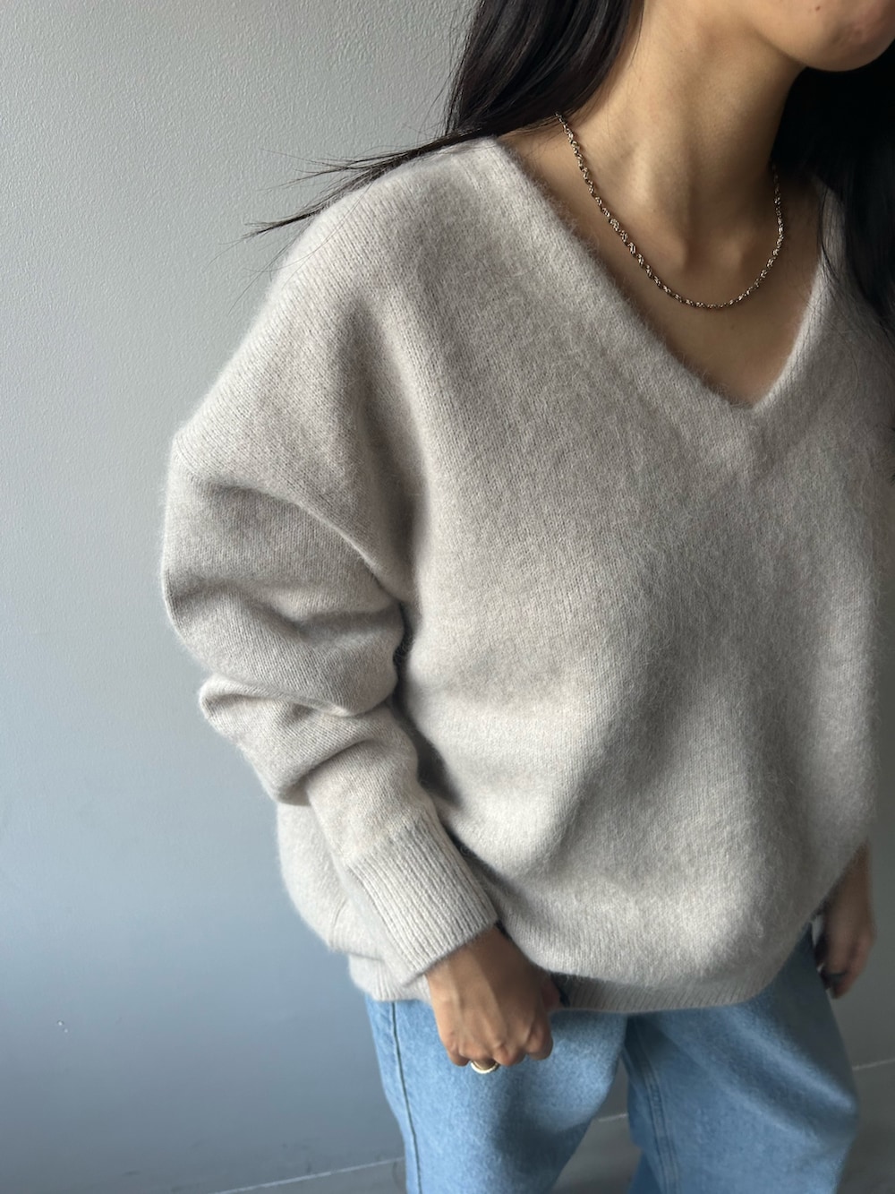 グレー系のニット/セーター、ブルー系のデニムパンツを着用したレディースの冬コーディネートの6枚目の写真