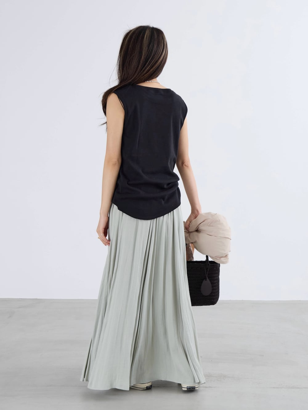 グリーン系のスカート、ブラック系のTシャツ/カットソーを着用したレディースの春コーディネートの3枚目の写真