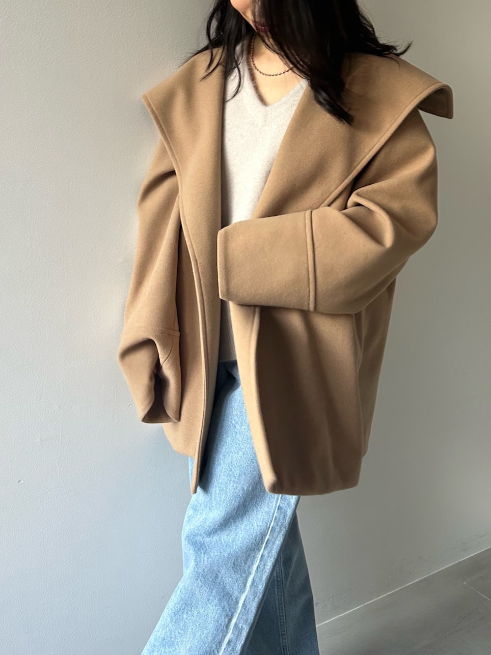 イエロー系のその他アウター、グレー系のニット/セーター、ブルー系のデニムパンツを着用したレディースの冬コーディネートの4枚目の写真