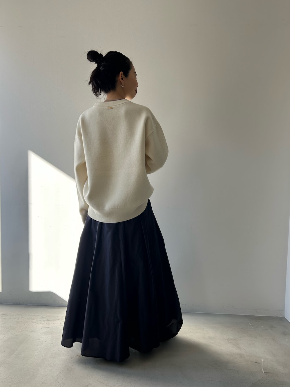 ブルー系のスカート、ホワイト系のニット/セーターを着用したレディースの冬コーディネートの3枚目の写真