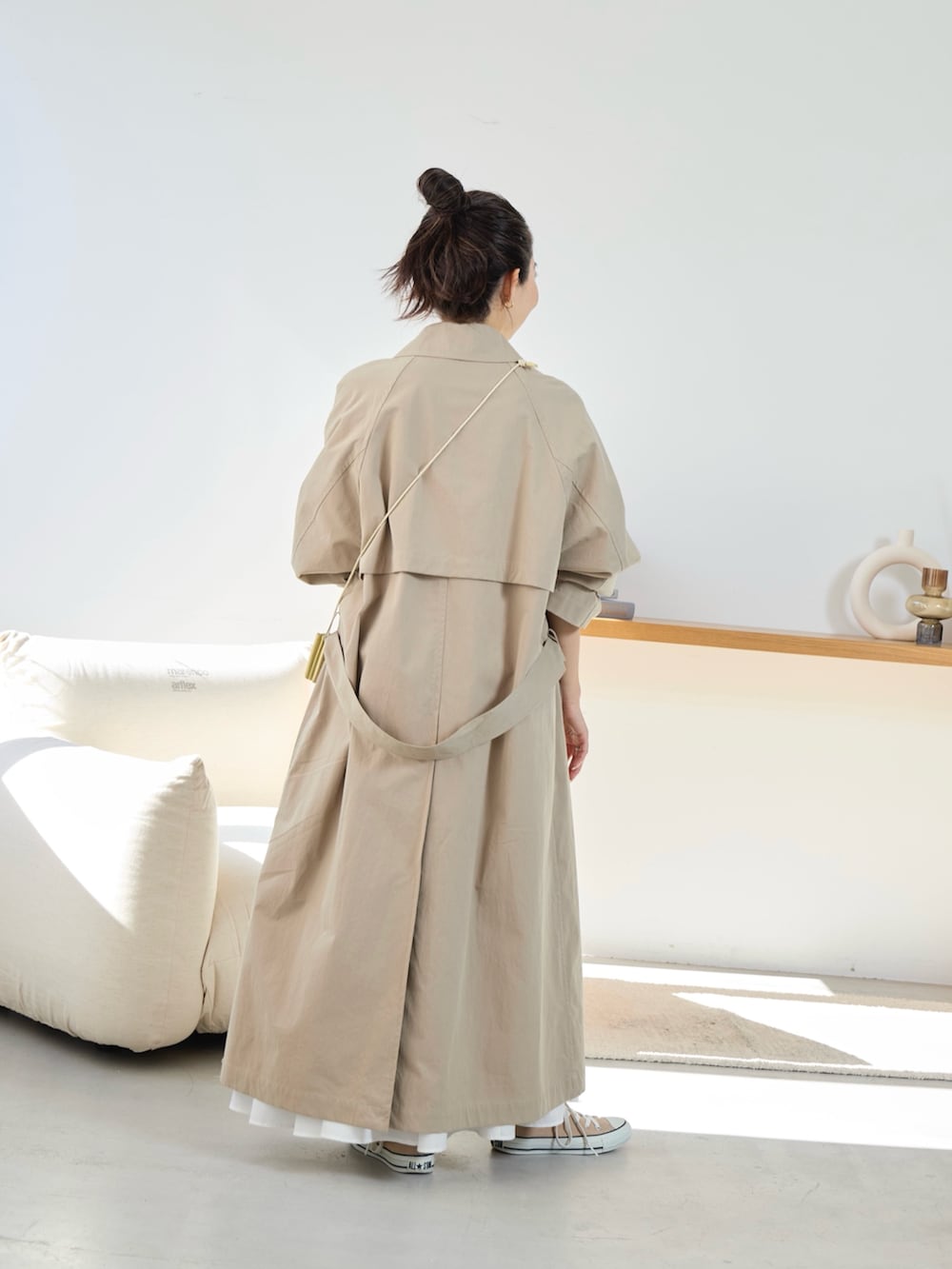 ベージュ系のトレンチコート、ホワイト系のスカートを着用したレディースの冬コーディネートの3枚目の写真