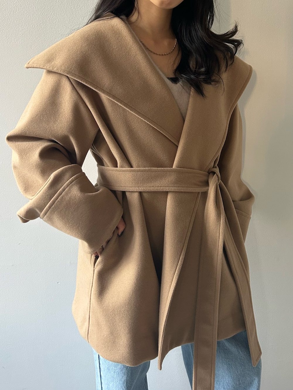 イエロー系のその他アウター、グレー系のニット/セーター、ブルー系のデニムパンツを着用したレディースの冬コーディネートの6枚目の写真