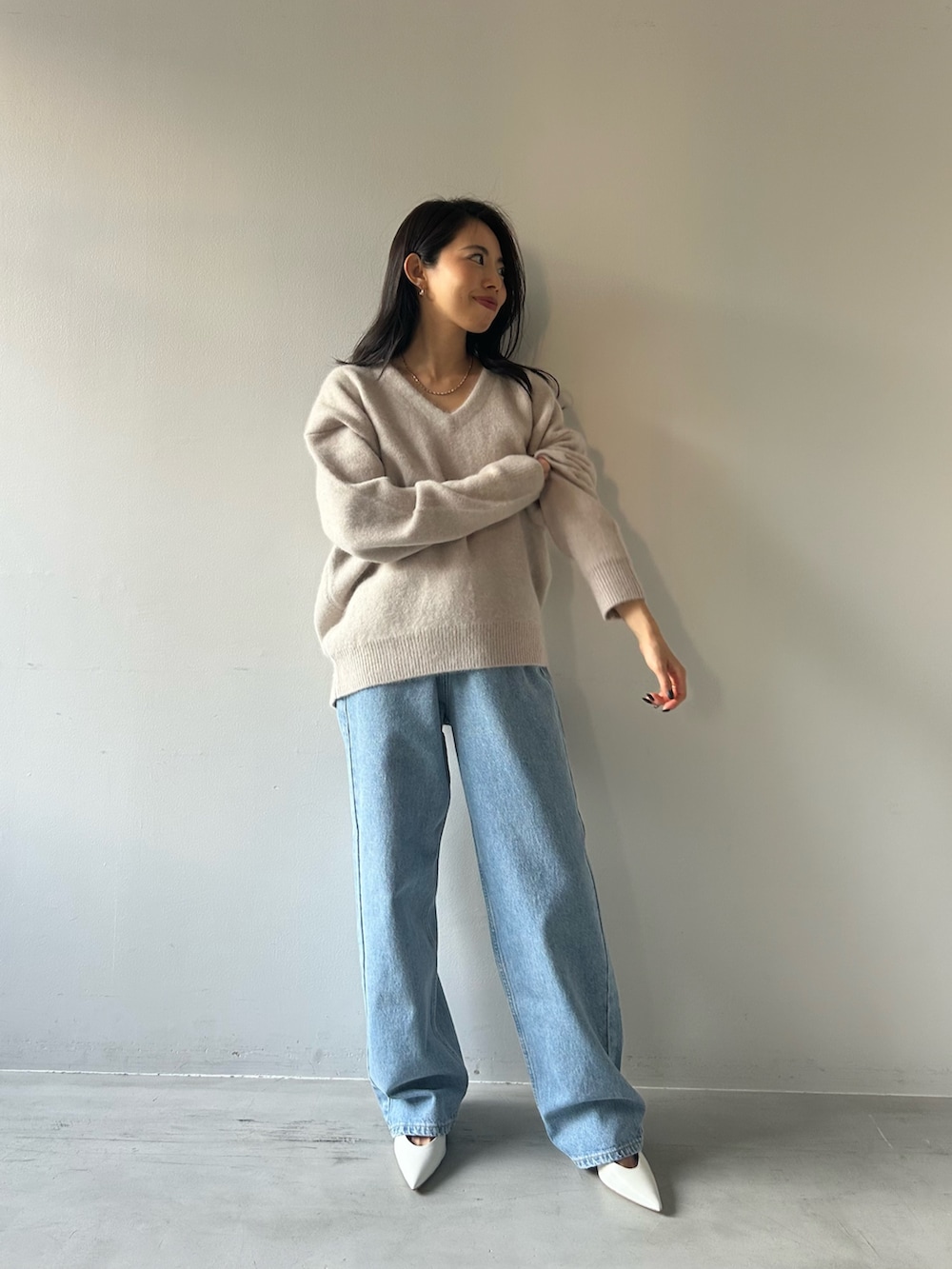 グレー系のニット/セーター、ブルー系のデニムパンツを着用したレディースの冬コーディネートの2枚目の写真