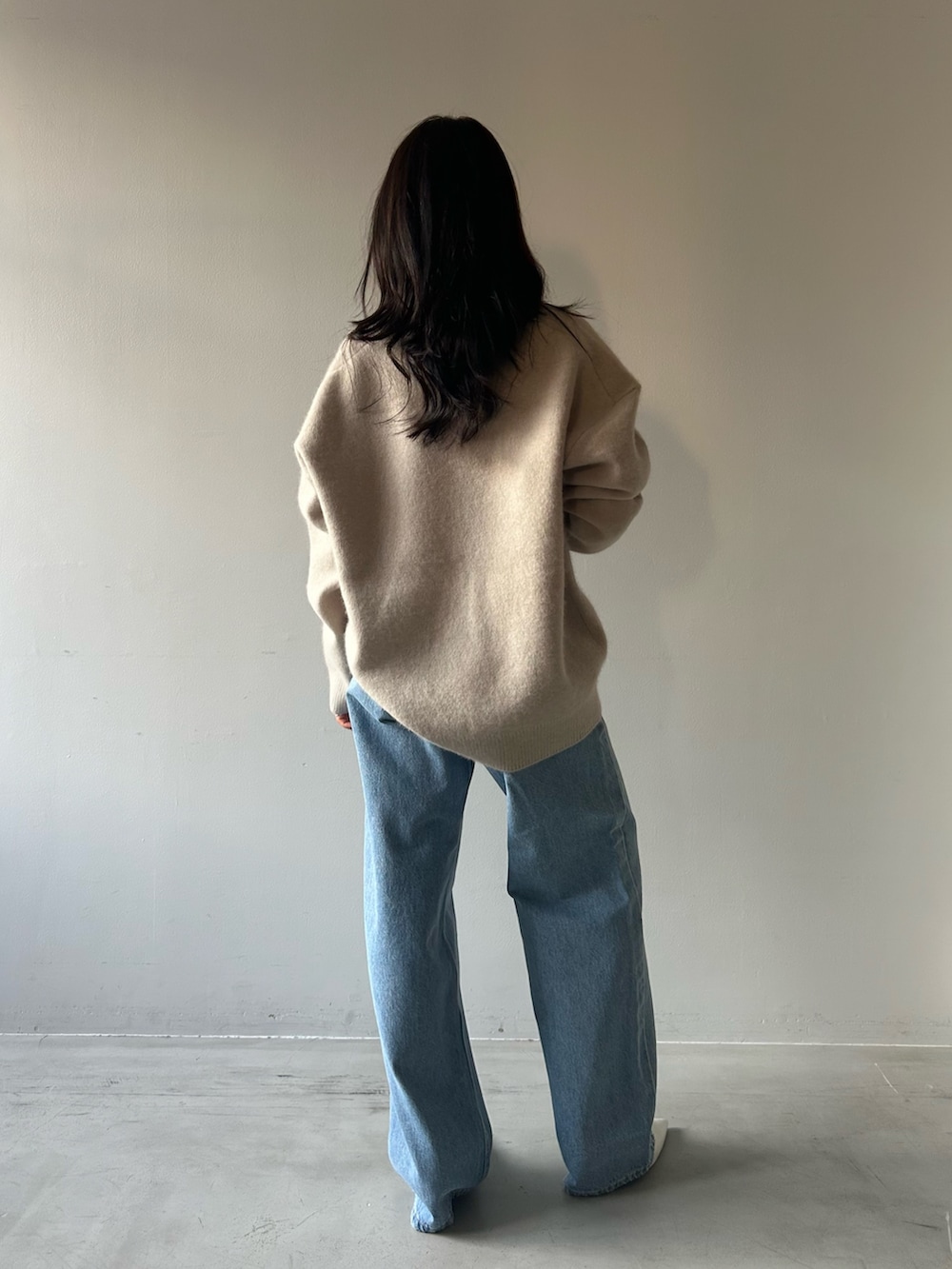 グレー系のニット/セーター、ブルー系のデニムパンツを着用したレディースの冬コーディネートの4枚目の写真