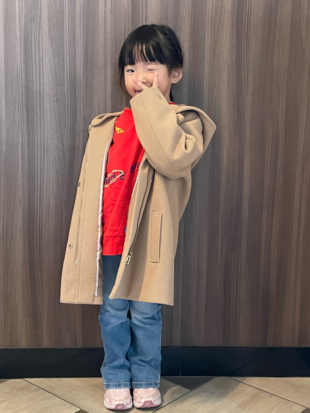 レッド系のスウェット、ベージュ系のジャケット/アウター、ブルー系のデニムパンツを着用したキッズの冬コーディネートの2枚目の写真