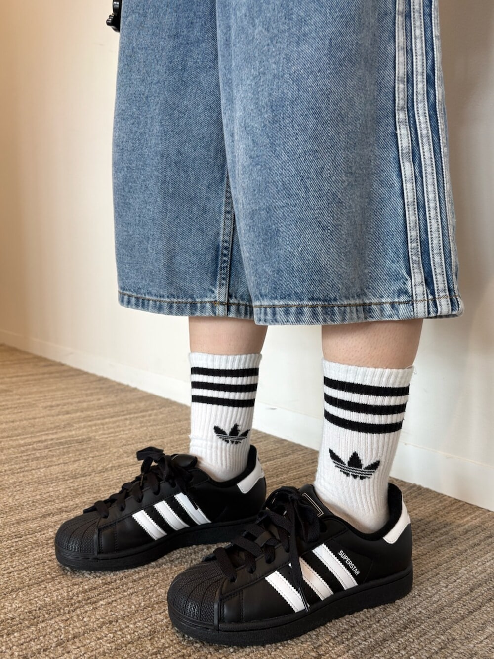 ブラック系のジャージ、ブルー系のデニムパンツ、ブラック系のスニーカーを着用したレディースの夏コーディネートの2枚目の写真