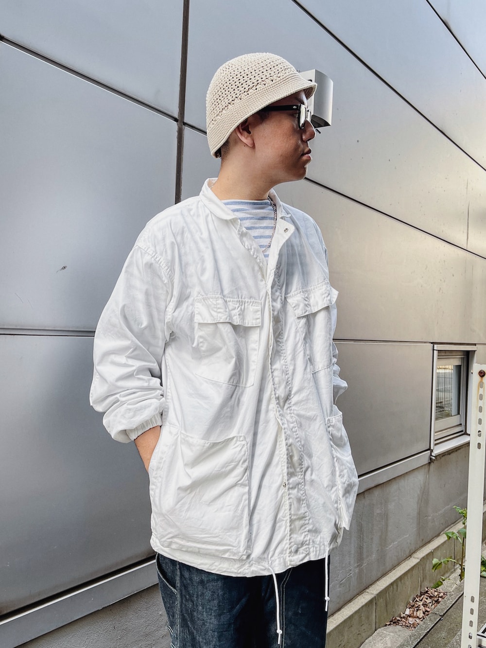 ホワイト系のTシャツ/カットソー、ホワイト系のミリタリージャケット、ブルー系のデニムパンツを着用したメンズの春コーディネートの2枚目の写真