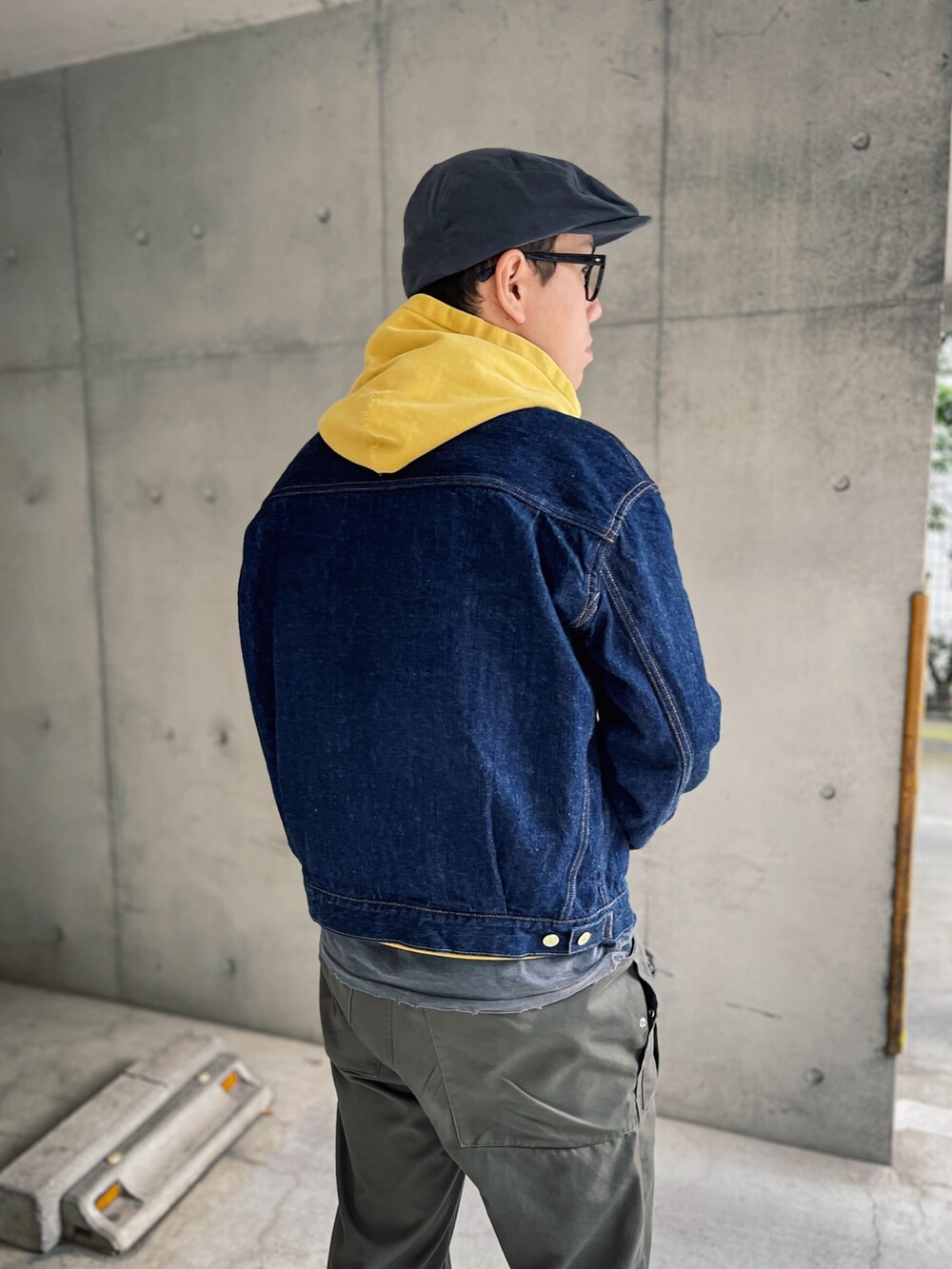 イエロー系のパーカー、ブルー系のデニムジャケット、ブラック系のスニーカーを着用したメンズの秋コーディネートの2枚目の写真