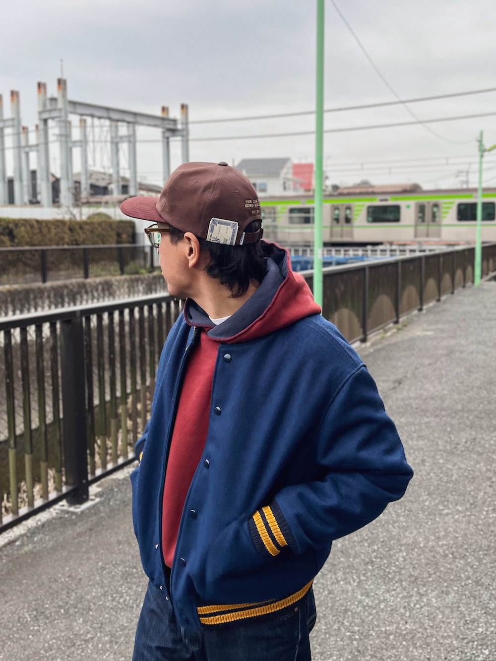 レッド系のパーカー、ブルー系のジャケット/アウター、ブルー系のデニムパンツを着用したメンズの春コーディネートの2枚目の写真