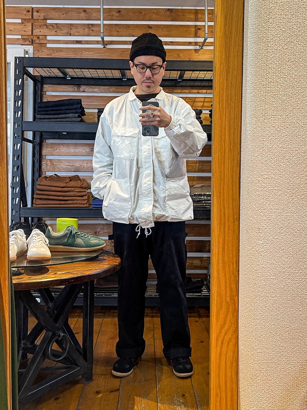 ブラック系のスウェット、ホワイト系のミリタリージャケット、ブラック系のパンツを着用したメンズの春コーディネートの2枚目の写真