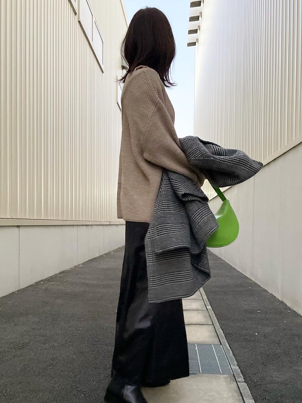 ベージュ系のニット/セーター、ブラック系のブーツ、グリーン系のハンドバッグを着用したレディースの冬コーディネートの4枚目の写真