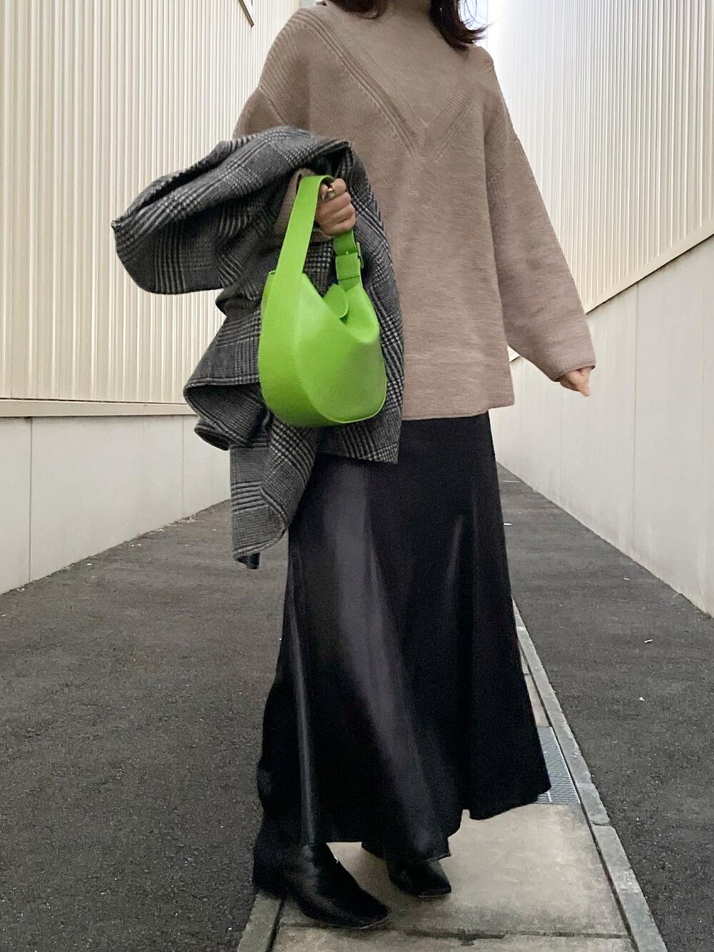 ベージュ系のニット/セーター、ブラック系のブーツ、グリーン系のハンドバッグを着用したレディースの冬コーディネートの2枚目の写真