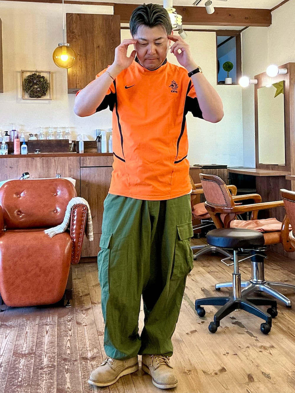 グリーン系のカーゴパンツ、ベージュ系のブーツ、オレンジ系のその他トップスを着用したメンズの夏コーディネートの2枚目の写真