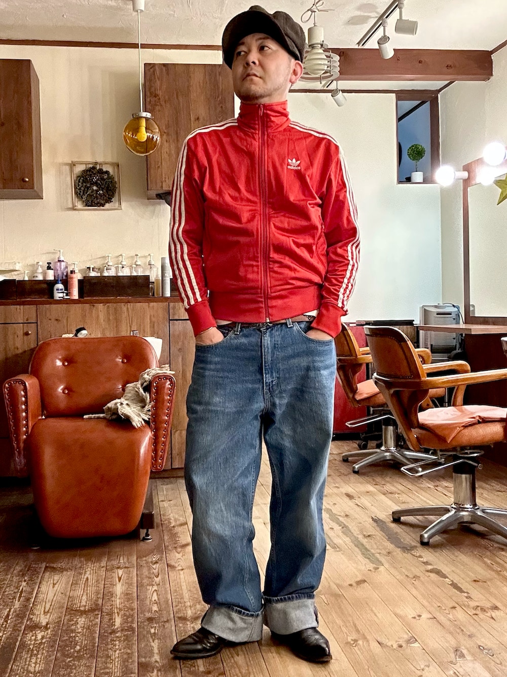 ブルー系のデニムパンツ、ブラック系のシューズ、レッド系のジャージを着用したメンズの冬コーディネートの2枚目の写真