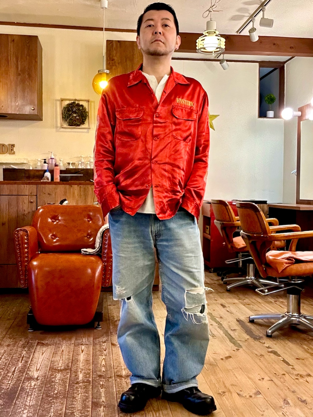 グリーン系のミリタリージャケット、ブラック系のシャツ/ブラウス、ブルー系のデニムパンツを着用したメンズの春コーディネートの2枚目の写真