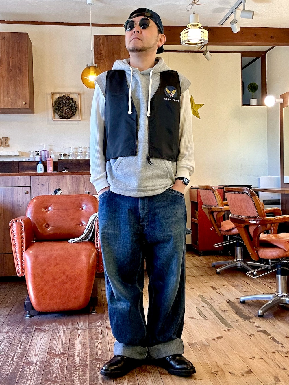 グレー系のパーカー、ブラック系のベスト、グリーン系のその他アウターを着用したメンズの春コーディネートの2枚目の写真