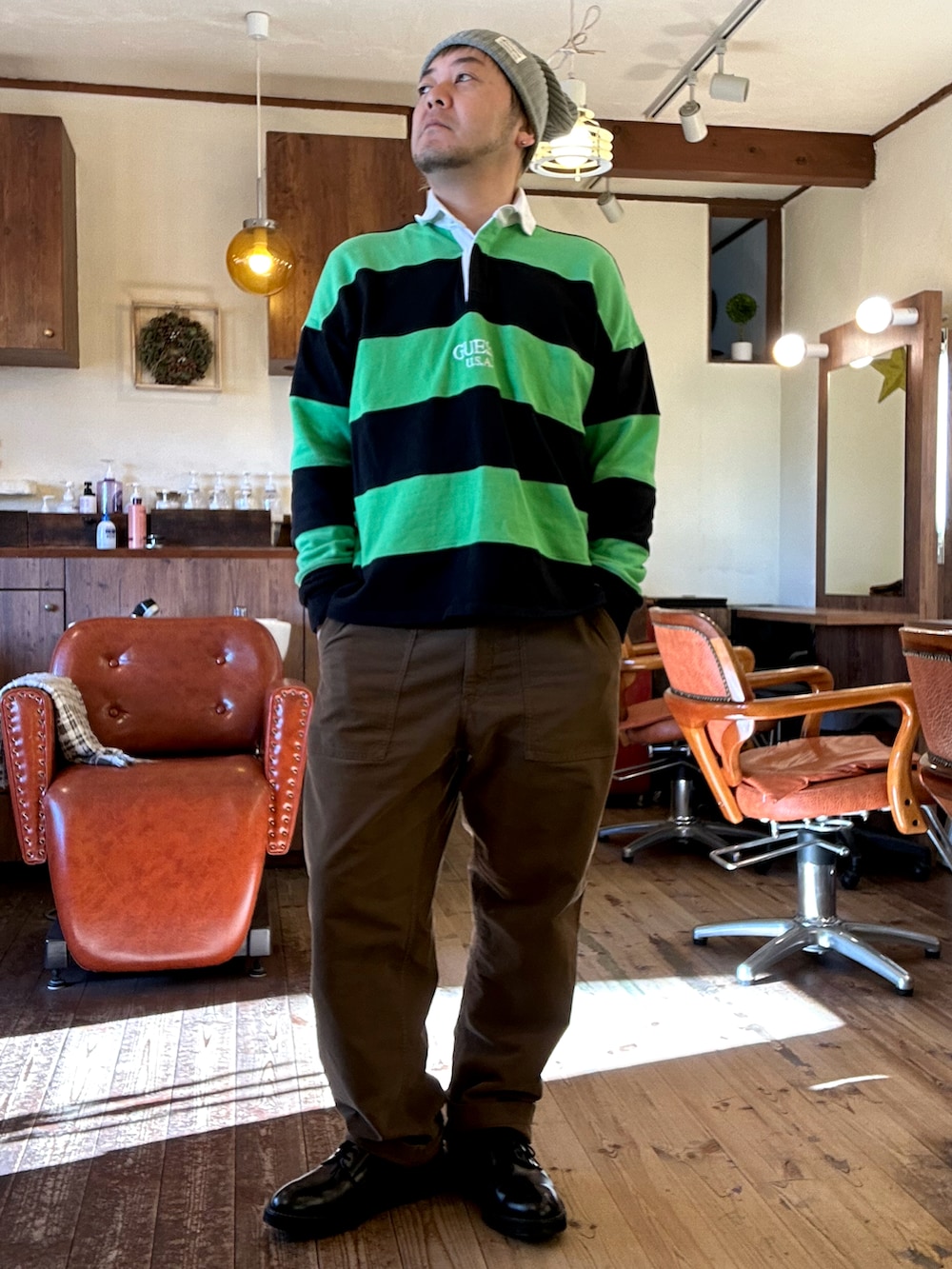 ブラウン系のパンツ、グリーン系のトップス、ブラック系のライダースジャケットを着用したメンズの冬コーディネートの2枚目の写真