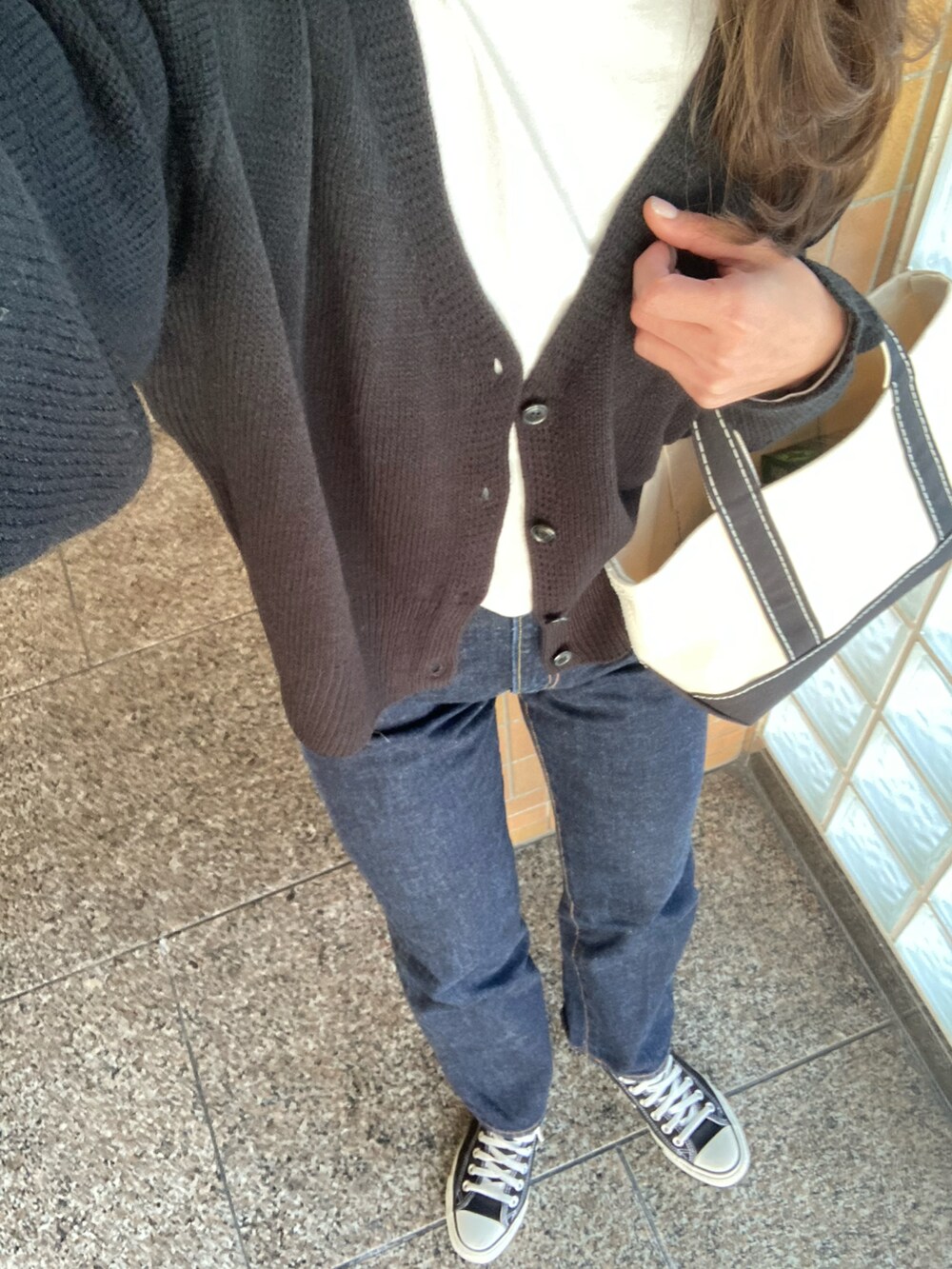 ホワイト系のTシャツ/カットソー、ブラック系のカーディガン/ボレロ、ブルー系のデニムパンツを着用したレディースの春コーディネートの2枚目の写真