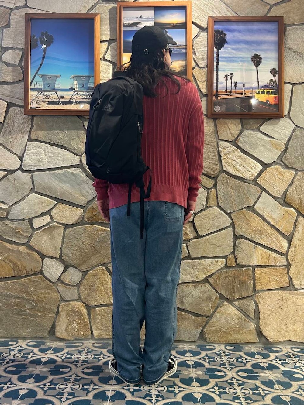 ブラック系のバックパック/リュック、ブラック系のスニーカー、ブルー系のデニムパンツを着用したメンズの秋コーディネートの4枚目の写真