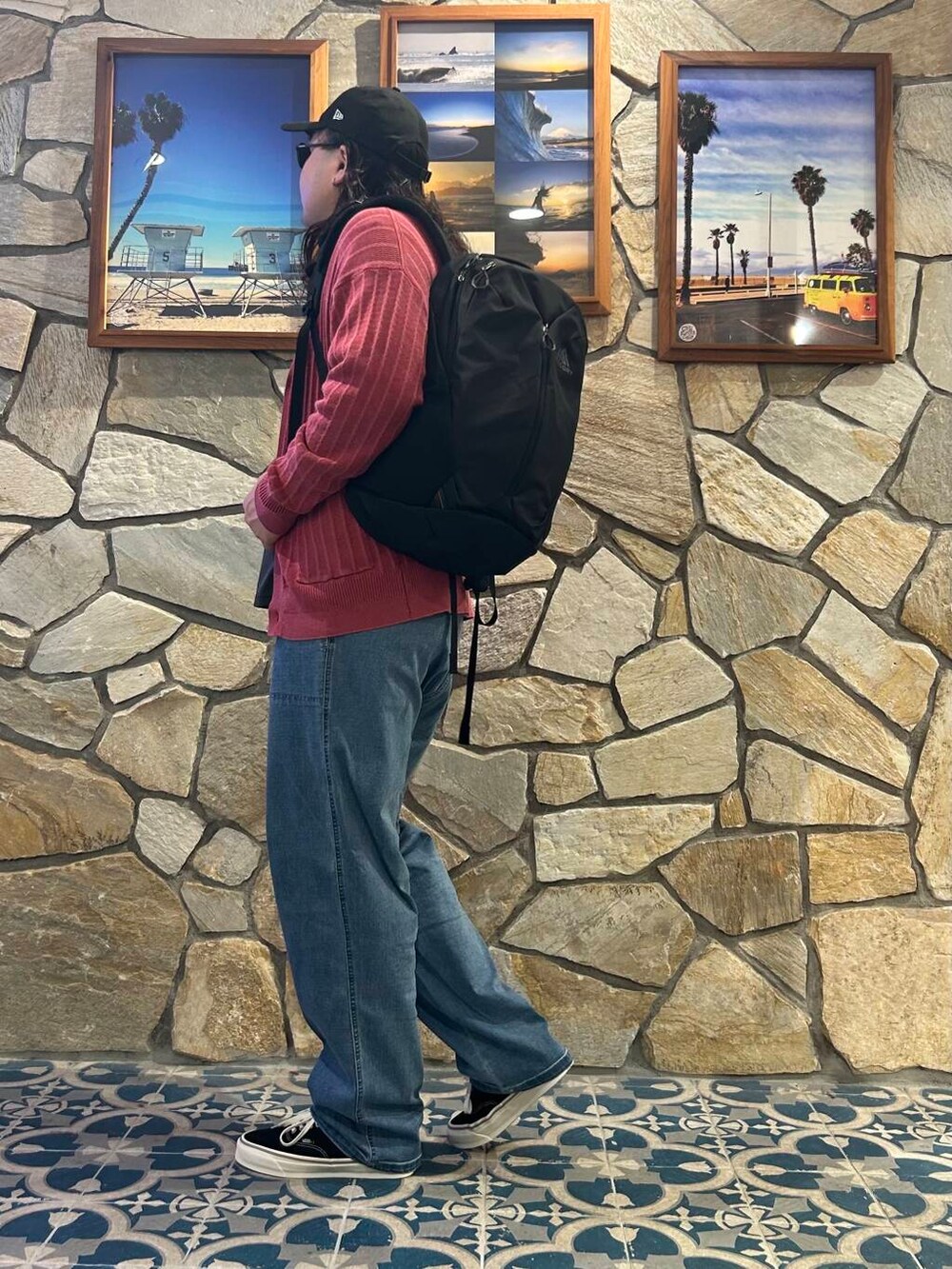 ブラック系のバックパック/リュック、ブラック系のスニーカー、ブルー系のデニムパンツを着用したメンズの秋コーディネートの3枚目の写真