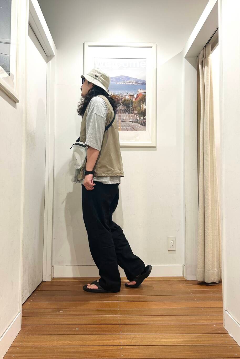 ブラック系のサンダル、グレー系のショルダーバッグ、ベージュ系のベストを着用したメンズの春コーディネートの3枚目の写真