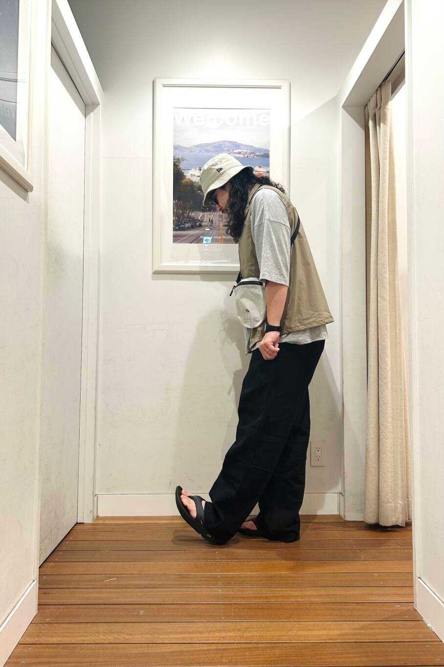 ブラック系のサンダル、グレー系のショルダーバッグ、ベージュ系のベストを着用したメンズの春コーディネートの2枚目の写真